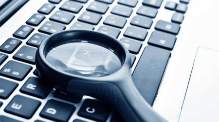 Close,Up,Of,Laptop,With,Magnifying,Glass.