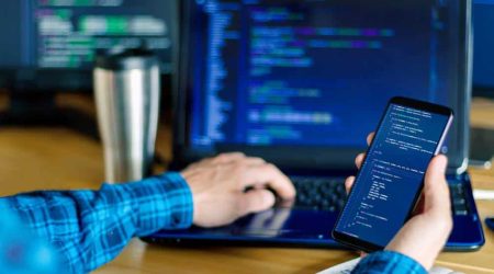 Closeup,Freelancer,Hand,Is,Holding,Smartphone,With,Program,Code.,Programmer